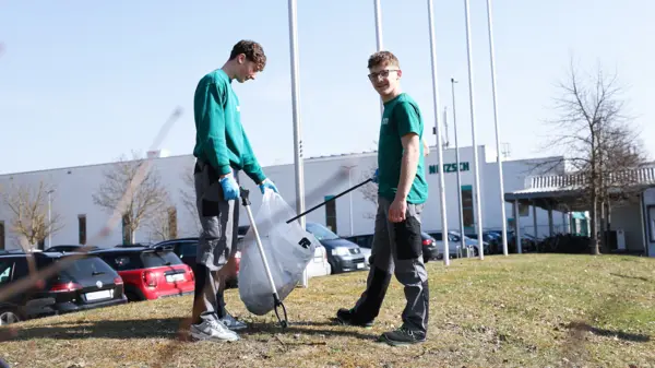 NETZSCH apprentices cleaning up litter around the company campus during the “Rama Dama” environmental campaign, wearing green shirts.