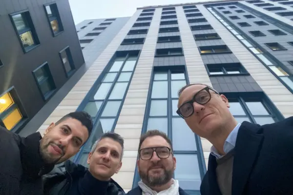 Vier Männer lächeln für ein Selfie vor einem modernen Bürogebäude in Bologna, das die neue italienische Regionalniederlassung von NETZSCH beherbergt.