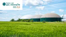 Renewable gas biogas plant with large digesters under blue sky in green agricultural field, Salón del Gas Renovable 2026.