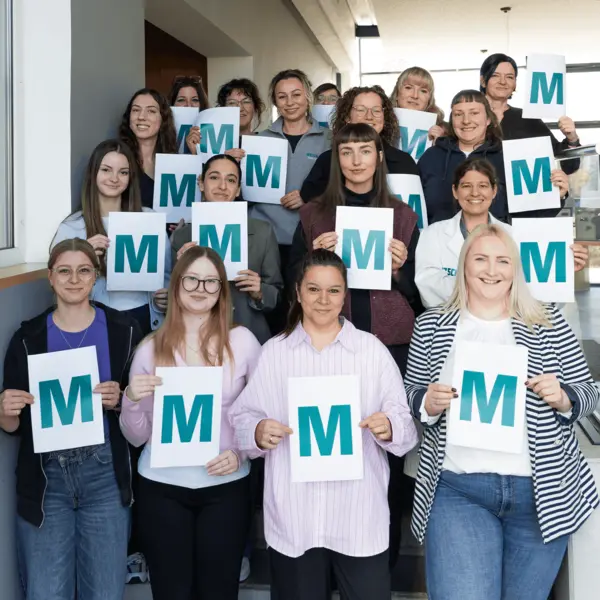 Female NETZSCH colleagues hold signs with "M" for a global photo initiative on International Women’s Day, celebrating diversity and strength.