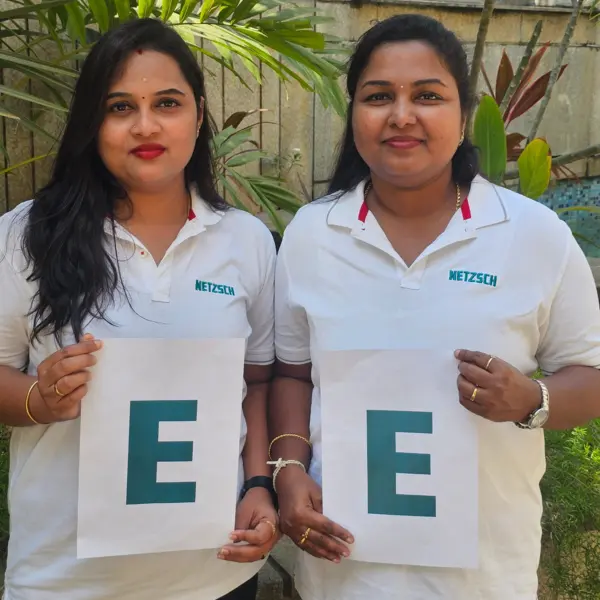 Two female colleagues from NETZSCH India hold letters "E" for a global initiative celebrating International Women's Day.