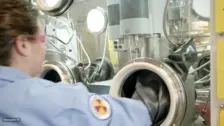 Scientist using glovebox equipment to safely handle radioactive molten salts for thermophysical analysis in nuclear research.